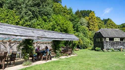 Family eating in the tea garden at Mottistone Gardens, under the shelter, on a sunny day.